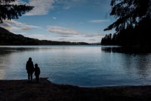 A serene view of a parent and child by a lake in San Carlos de Bariloche, Argentina.